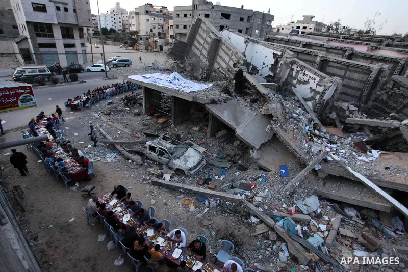 Palestinian families break their fast next to a destroyed building during recent confrontation between Hamas and Israel, during the Muslim holy fasting month of Ramadan, in Gaza city on May 18, 2019. Photo by Mahmoud Ajj...