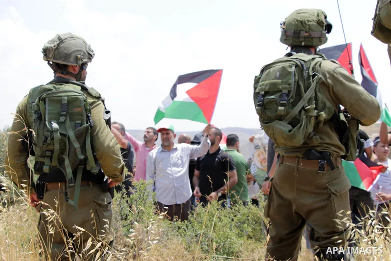 Members of Israeli security forces stand guard as Palestinian protesters demonstrate against the expropriation of Palestinian agricultural land by Israel, in the village of Azmut, near the West Bank city of Nablus on Jun...