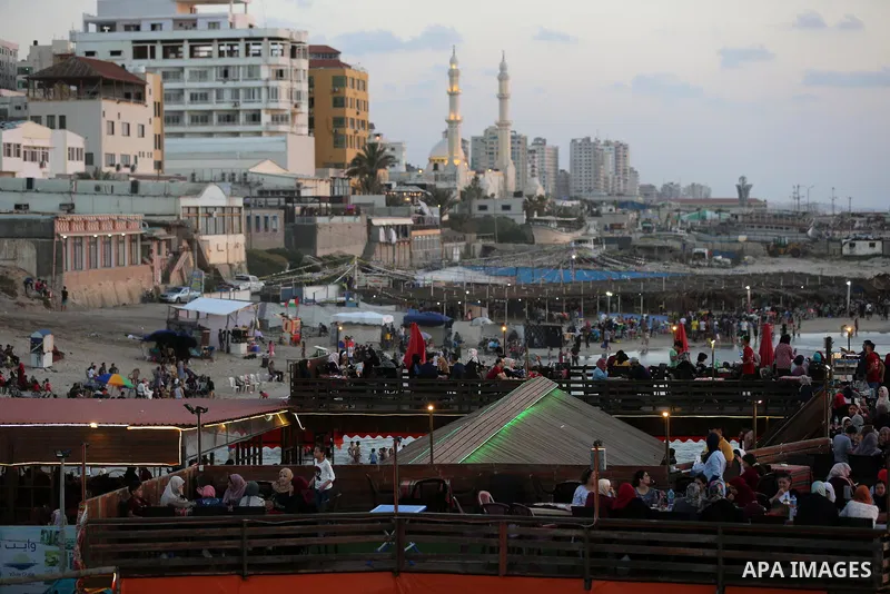 Palestinians site in a cafe on the beach ialong the shore of the Mediterranean Sea as they escape from the summer heat, in Gaza City July 01, 2019. Photo by Ashraf Amra