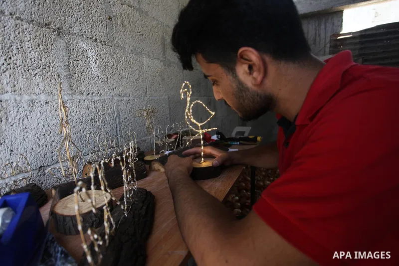 Muath Abu el-Qumboz, 24, A Palestinian man works on handmade gifts at his house, in Gaza city on July 02, 2019. Abu el-Qumboz, uses wood and wires to form different shapes and make lighten gifts from simple materials. Ph...