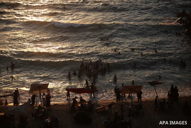 Palestinians enjoy at the beach along the shore of the Mediterranean Sea during the sunset, in Gaza City July 05, 2019. Photo by Mahmoud Ajjour