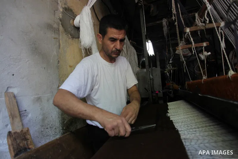 Palestinian workers weave carpets in a workshop in Gaza city on July 06, 2019. Weaving sheep's wool into traditional carpets is one oldest professions, it takes skill, patience and steady hand. Photo by Mahmoud Ajjour