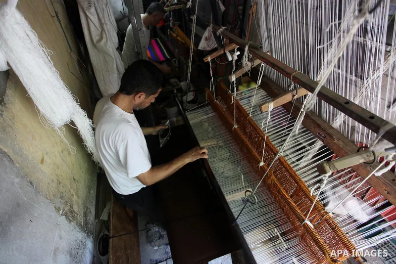 Palestinian workers weave carpets in a workshop in Gaza city on July 06, 2019. Weaving sheep's wool into traditional carpets is one oldest professions, it takes skill, patience and steady hand. Photo by Mahmoud Ajjour