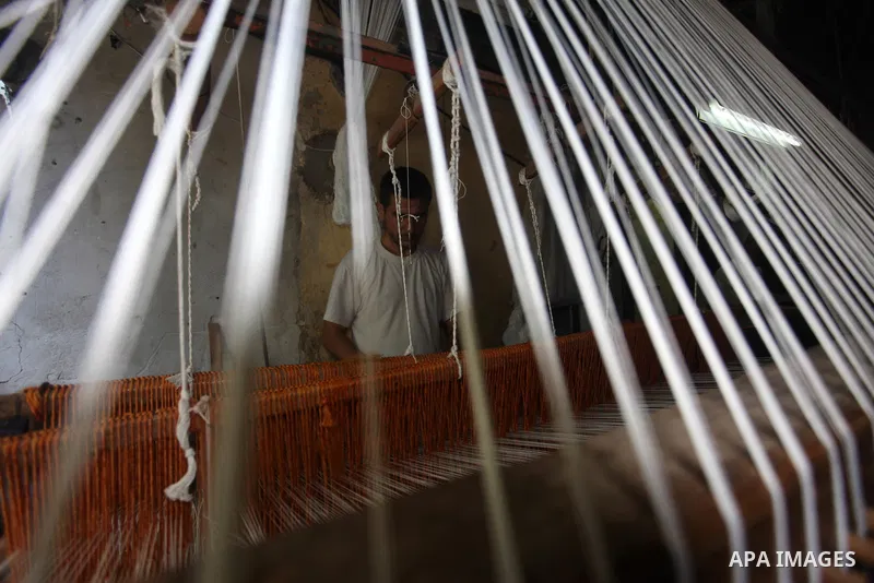 Palestinian workers weave carpets in a workshop in Gaza city on July 06, 2019. Weaving sheep's wool into traditional carpets is one oldest professions, it takes skill, patience and steady hand. Photo by Mahmoud Ajjour