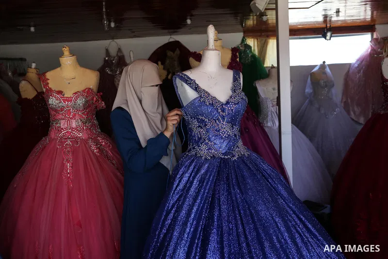 Palestinian woman Sabrin al-Jabri, 34, works with her children at her shop in renting and selling wedding dresses, in Khan Younis in the southern Gaza Strip, July 06, 2019. Al-Jabri graduated from the Department of Medic...