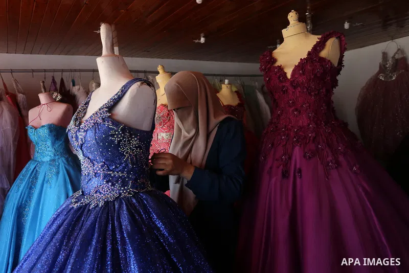Palestinian woman Sabrin al-Jabri, 34, works with her children at her shop in renting and selling wedding dresses, in Khan Younis in the southern Gaza Strip, July 06, 2019. Al-Jabri graduated from the Department of Medic...