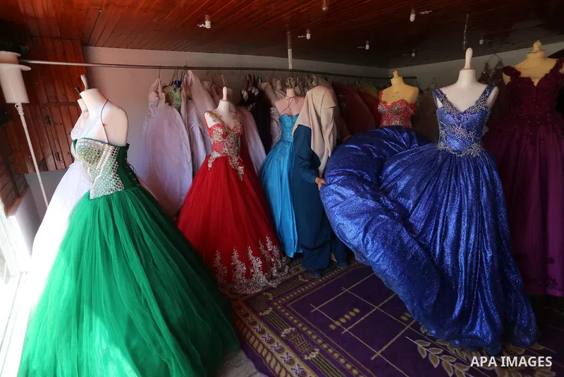 Palestinian woman Sabrin al-Jabri, 34, works with her children at her shop in renting and selling wedding dresses, in Khan Younis in the southern Gaza Strip, July 06, 2019. Al-Jabri graduated from the Department of Medic...