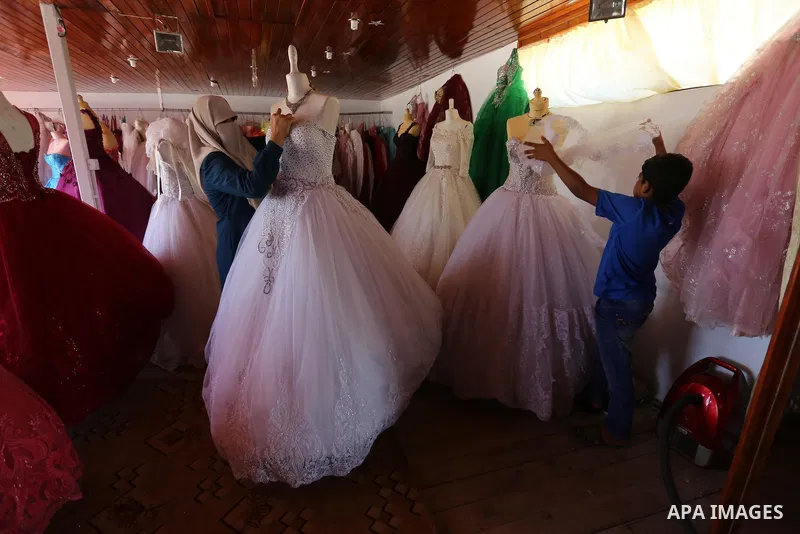 Palestinian woman Sabrin al-Jabri, 34, works with her children at her shop in renting and selling wedding dresses, in Khan Younis in the southern Gaza Strip, July 06, 2019. Al-Jabri graduated from the Department of Medic...