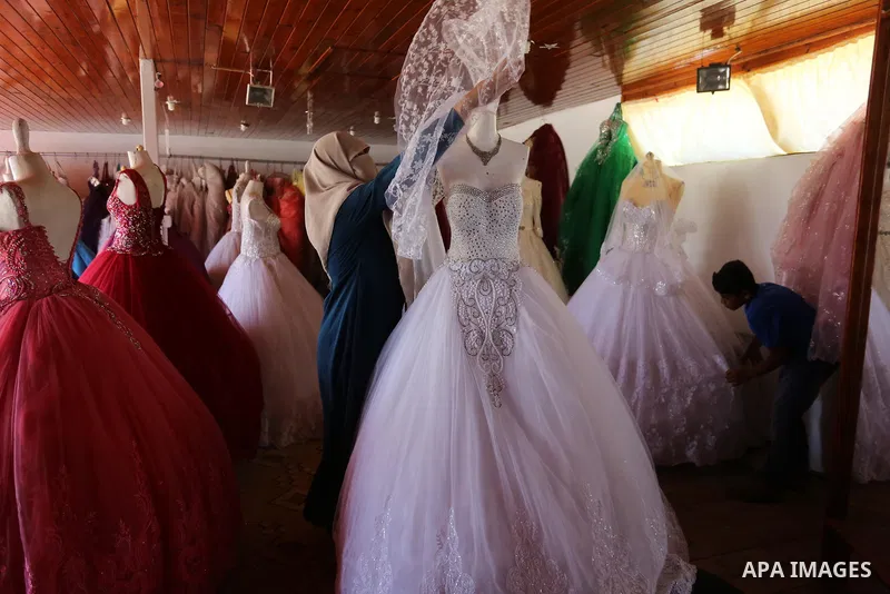 Palestinian woman Sabrin al-Jabri, 34, works with her children at her shop in renting and selling wedding dresses, in Khan Younis in the southern Gaza Strip, July 06, 2019. Al-Jabri graduated from the Department of Medic...