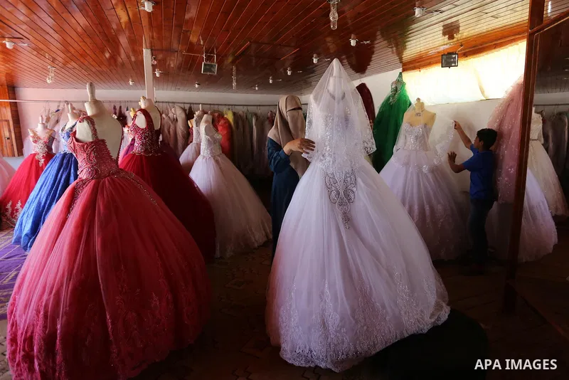 Palestinian woman Sabrin al-Jabri, 34, works with her children at her shop in renting and selling wedding dresses, in Khan Younis in the southern Gaza Strip, July 06, 2019. Al-Jabri graduated from the Department of Medic...