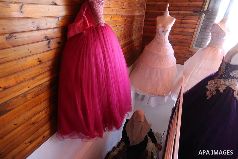 Palestinian woman Sabrin al-Jabri, 34, works with her children at her shop in renting and selling wedding dresses, in Khan Younis in the southern Gaza Strip, July 06, 2019. Al-Jabri graduated from the Department of Medic...