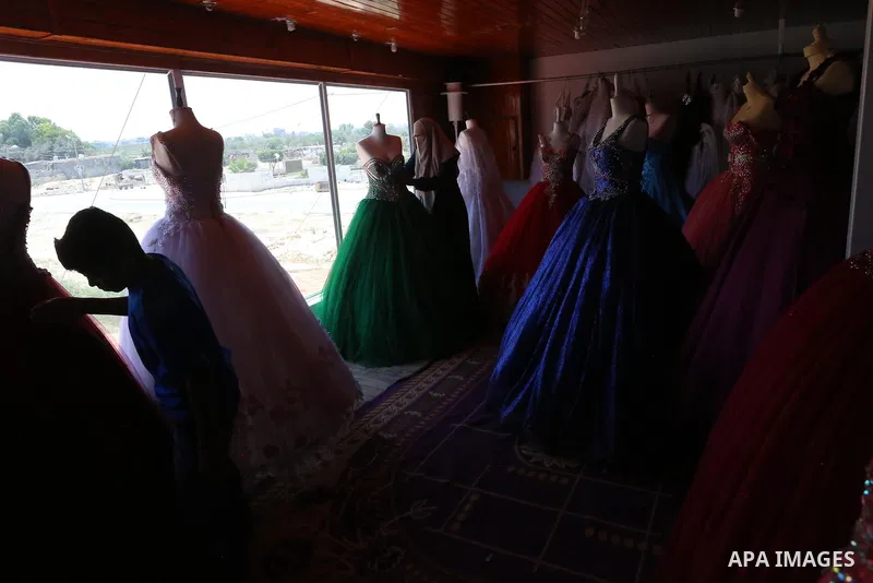 Palestinian woman Sabrin al-Jabri, 34, works with her children at her shop in renting and selling wedding dresses, in Khan Younis in the southern Gaza Strip, July 06, 2019. Al-Jabri graduated from the Department of Medic...