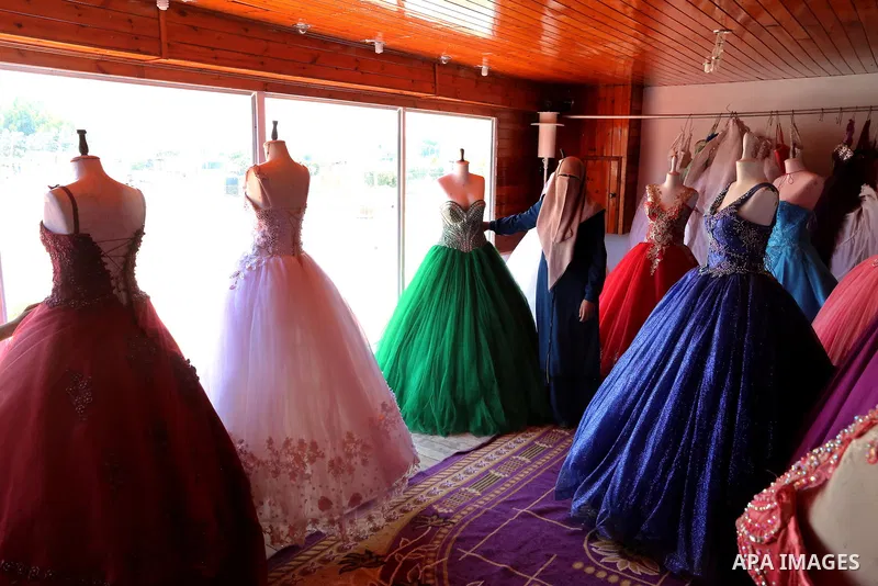 Palestinian woman Sabrin al-Jabri, 34, works with her children at her shop in renting and selling wedding dresses, in Khan Younis in the southern Gaza Strip, July 06, 2019. Al-Jabri graduated from the Department of Medic...