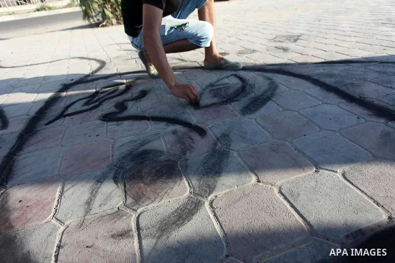Moawia Ashour, 24, a Palestinian man uses coal to draw on the ground near his street cafe, at the beach of Gaza city, July 30, 2019. Photo by Mahmoud Ajjour