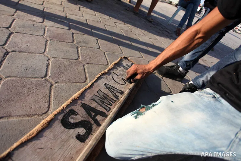 Moawia Ashour, 24, a Palestinian man uses coal to draw on a wooden board near his street cafe, at the beach of Gaza city, July 30, 2019. Photo by Mahmoud Ajjour