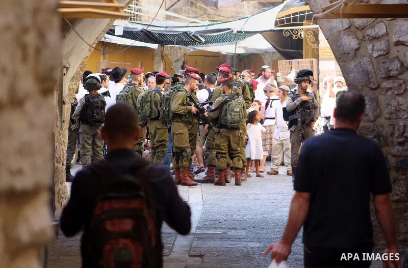 Israeli soldiers stand guard as Jewish settlers tour of the streets in the Old City of the West Bank city of Hebron, on August 24, 2019. Photo by Mosab Shawer