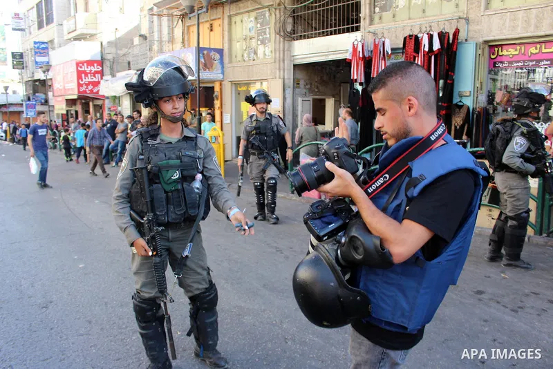 A member of Israeli security forces stops a Palestinian photographer prior to the arrival of the Israeli prime minister to attend a state memorial ceremony at the Ibrahimi mosque, in the West Bank city of Hebron on Septe...