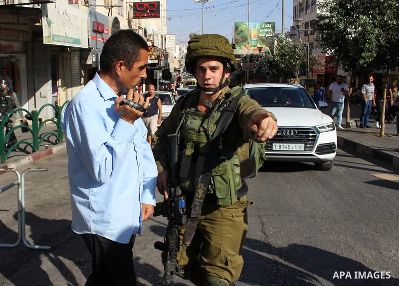 A member of Israeli security forces stops a Palestinian photographer prior to the arrival of the Israeli prime minister to attend a state memorial ceremony at the Ibrahimi mosque, in the West Bank city of Hebron on Septe...