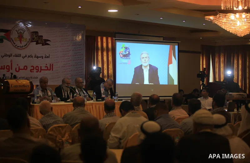Palestinians watch while Secretary General of the Islamic Jihad Movement Ziad al-Nakhla speaking via a video link during the national meeting coming out of Oslo in Gaza City, on September 17, 2019. Photo by Mahmoud Ajjou...