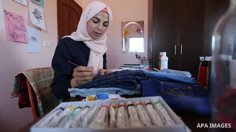 Palestinian artist Manal al-Astal, 20, paints on the clothes at her house in Khan Younis in the southern of Gaza strip, on September 18, 2019. al-Astal has drawing talent. Photo by Ashraf Amra