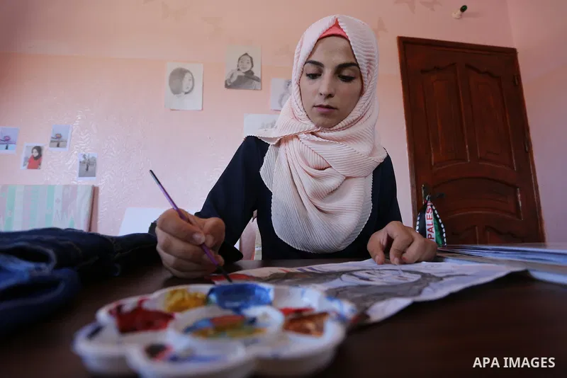 Palestinian artist Manal al-Astal, 20, paints on the clothes at her house in Khan Younis in the southern of Gaza strip, on September 18, 2019. al-Astal has drawing talent. Photo by Ashraf Amra
