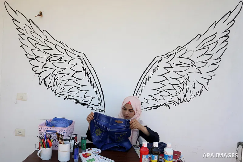 Palestinian artist Manal al-Astal, 20, paints on the clothes at her house in Khan Younis in the southern of Gaza strip, on September 18, 2019. al-Astal has drawing talent. Photo by Ashraf Amra