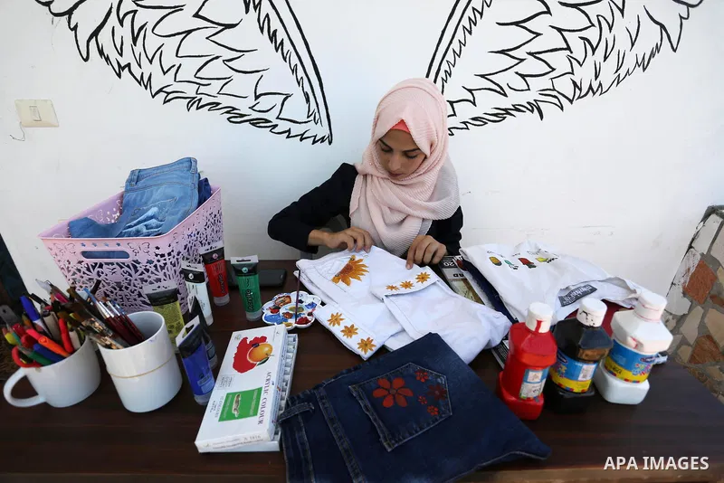 Palestinian artist Manal al-Astal, 20, paints on the clothes at her house in Khan Younis in the southern of Gaza strip, on September 18, 2019. al-Astal has drawing talent. Photo by Ashraf Amra