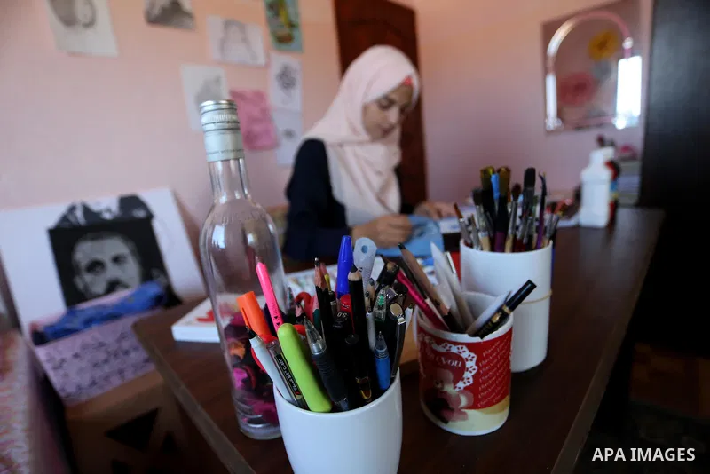 Palestinian artist Manal al-Astal, 20, paints on the clothes at her house in Khan Younis in the southern of Gaza strip, on September 18, 2019. al-Astal has drawing talent. Photo by Ashraf Amra
