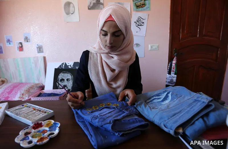 Palestinian artist Manal al-Astal, 20, paints on the clothes at her house in Khan Younis in the southern of Gaza strip, on September 18, 2019. al-Astal has drawing talent. Photo by Ashraf Amra