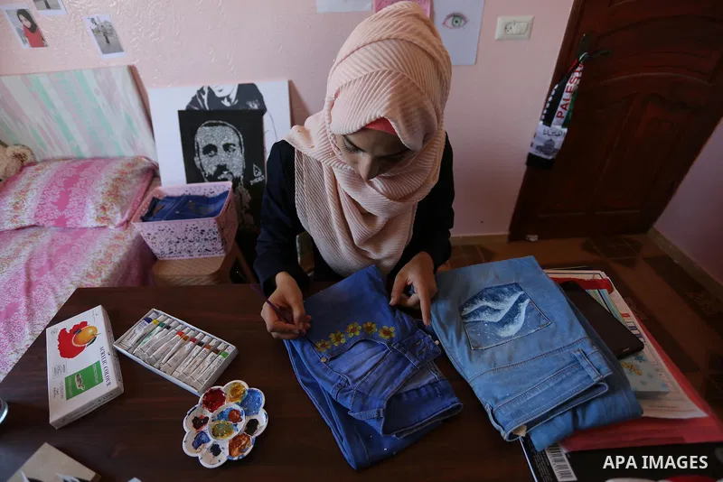 Palestinian artist Manal al-Astal, 20, paints on the clothes at her house in Khan Younis in the southern of Gaza strip, on September 18, 2019. al-Astal has drawing talent. Photo by Ashraf Amra