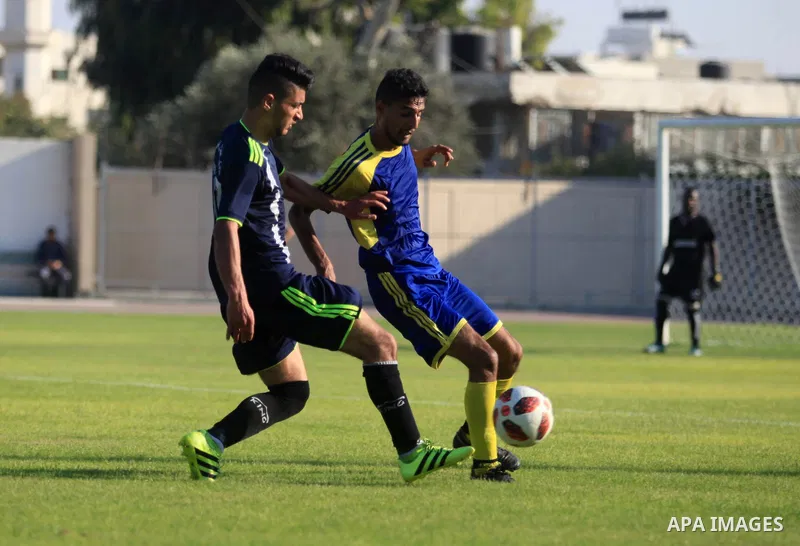 Palestinian football players of Etihad Beit Hanoun (blue) and Alhilal (Dark blue) compete during match premier League in Alyarmuk stadium, in Gaza City on September 22, 2019. Photo by Mahmoud Ajjour