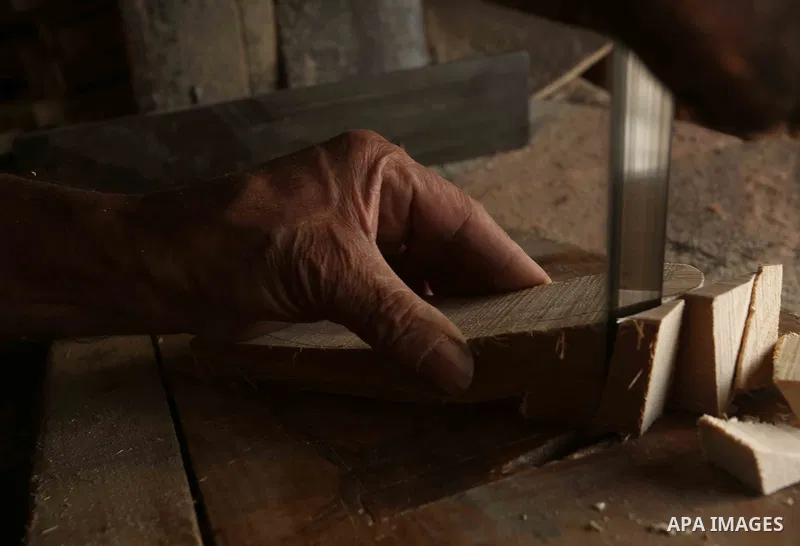A Palestinian man Waleed Khudair, 69, works on wood to makes the Sabot "wooden shoes" at his workshop in the West Bank city of Nablus, on September 25, 2019. Photo by Shadi Jarar'ah