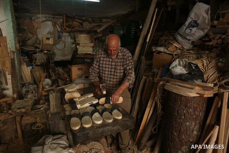 A Palestinian man Waleed Khudair, 69, works on wood to makes the Sabot "wooden shoes" at his workshop in the West Bank city of Nablus, on September 25, 2019. Photo by Shadi Jarar'ah