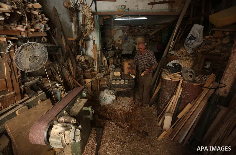 A Palestinian man Waleed Khudair, 69, works on wood to makes the Sabot "wooden shoes" at his workshop in the West Bank city of Nablus, on September 25, 2019. Photo by Shadi Jarar'ah