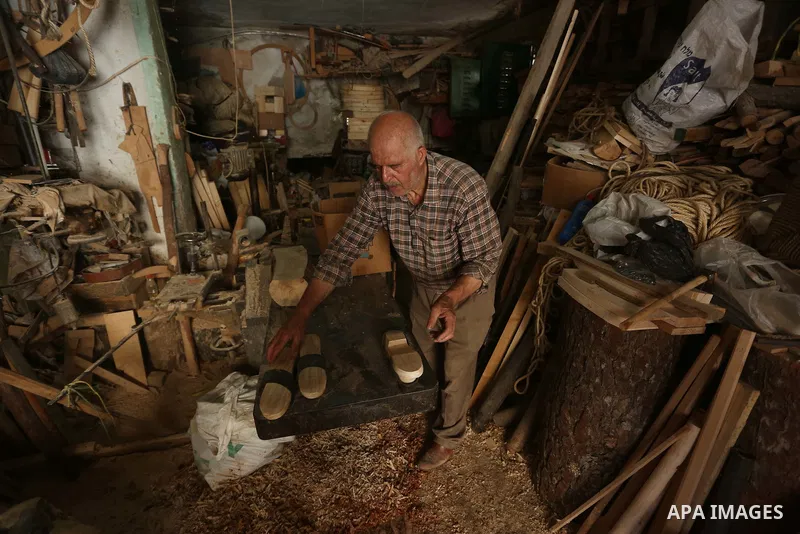 A Palestinian man Waleed Khudair, 69, works on wood to makes the Sabot "wooden shoes" at his workshop in the West Bank city of Nablus, on September 25, 2019. Photo by Shadi Jarar'ah