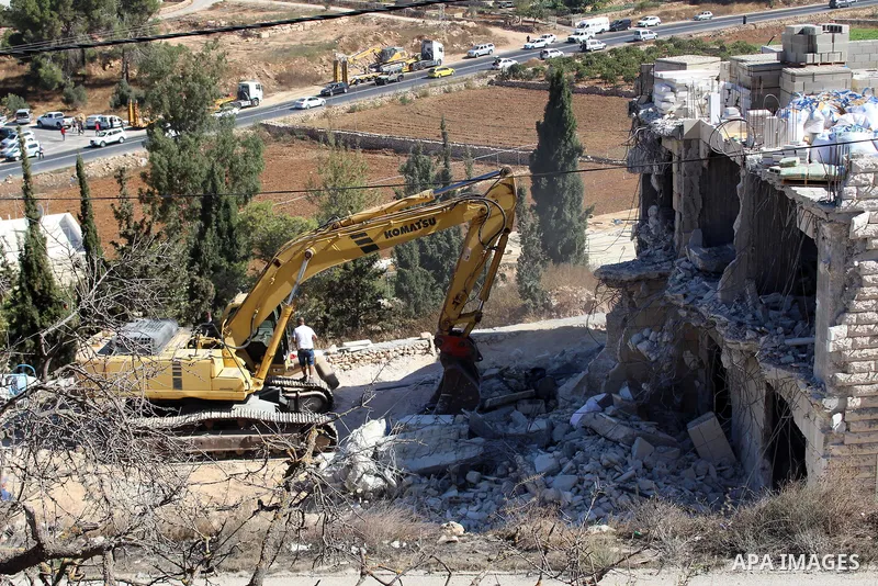 An Israeli bulldozer demolishes a Palestinian building which does not have the Israeli needed permits on the outskirts of Dura village near the West Bank city of Hebron on September 25, 2019. Israeli bulldozers demolishe...