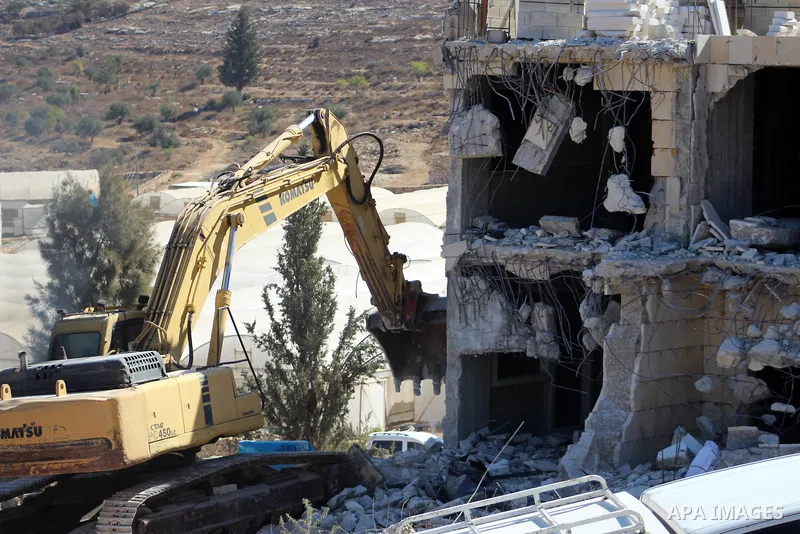 An Israeli bulldozer demolishes a Palestinian building which does not have the Israeli needed permits on the outskirts of Dura village near the West Bank city of Hebron on September 25, 2019. Israeli bulldozers demolishe...