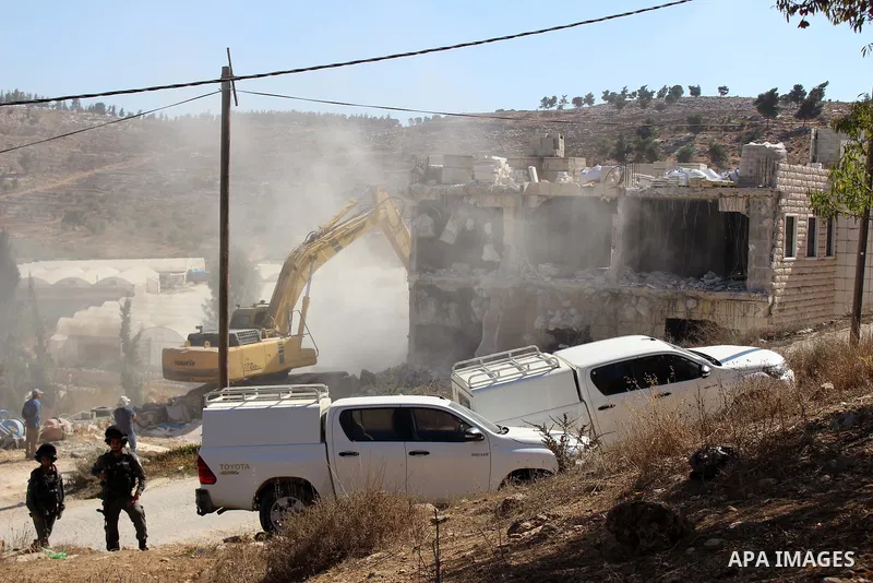 Israeli border police guard as Israeli bulldozer demolishes a Palestinian building which does not have the Israeli needed permits on the outskirts of Dura village near the West Bank city of Hebron on September 25, 2019....