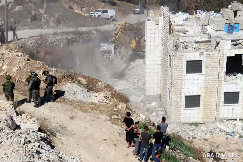An Israeli bulldozer demolishes a Palestinian building which does not have the Israeli needed permits on the outskirts of Dura village near the West Bank city of Hebron on September 25, 2019. Israeli bulldozers demolishe...