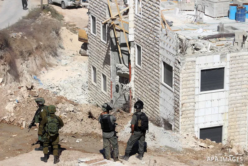 Israeli border police guard as Israeli bulldozer demolishes a Palestinian building which does not have the Israeli needed permits on the outskirts of Dura village near the West Bank city of Hebron on September 25, 2019....