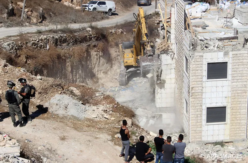 Israeli border police guard as Israeli bulldozer demolishes a Palestinian building which does not have the Israeli needed permits on the outskirts of Dura village near the West Bank city of Hebron on September 25, 2019....