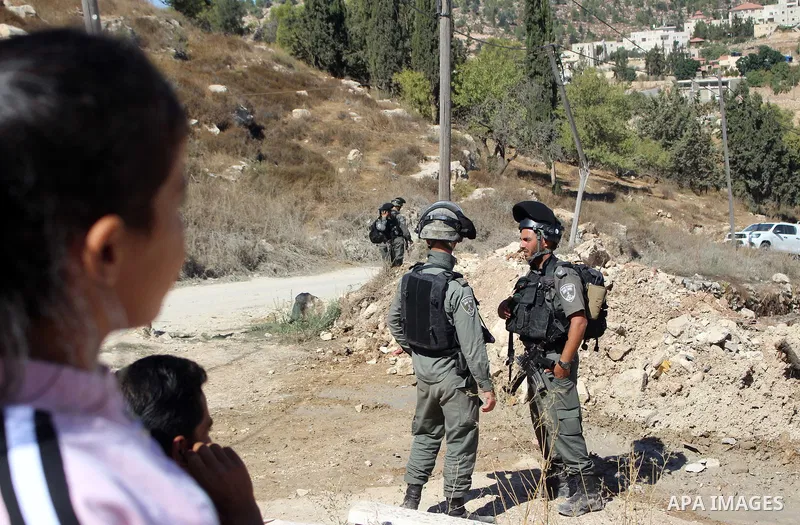 Israeli border police guard as Israeli bulldozer demolishes a Palestinian building which does not have the Israeli needed permits on the outskirts of Dura village near the West Bank city of Hebron on September 25, 2019....