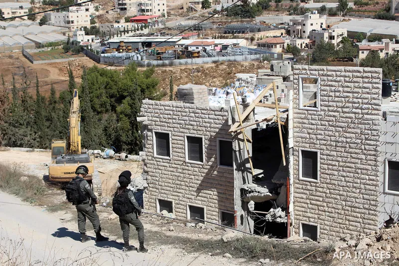 Israeli border police guard as Israeli bulldozer demolishes a Palestinian building which does not have the Israeli needed permits on the outskirts of Dura village near the West Bank city of Hebron on September 25, 2019....