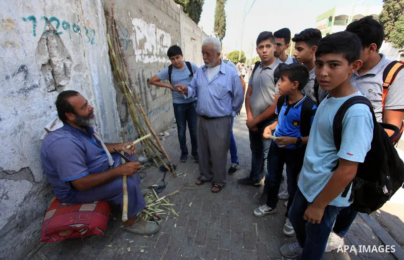 A Palestinian man sells sugar cane to students at a street, in Gaza city, on October 2, 2019. Photo by Mahmoud Ajjour
