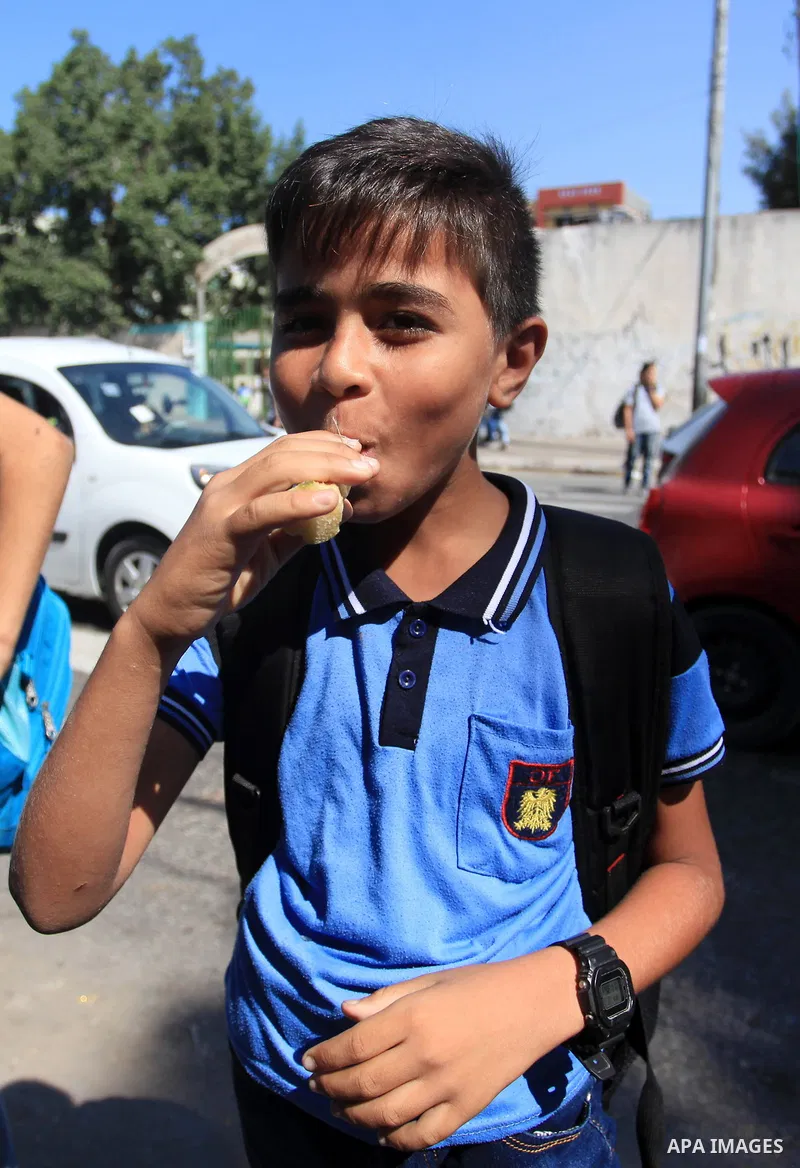 A Palestinian man sells sugar cane to students at a street, in Gaza city, on October 2, 2019. Photo by Mahmoud Ajjour
