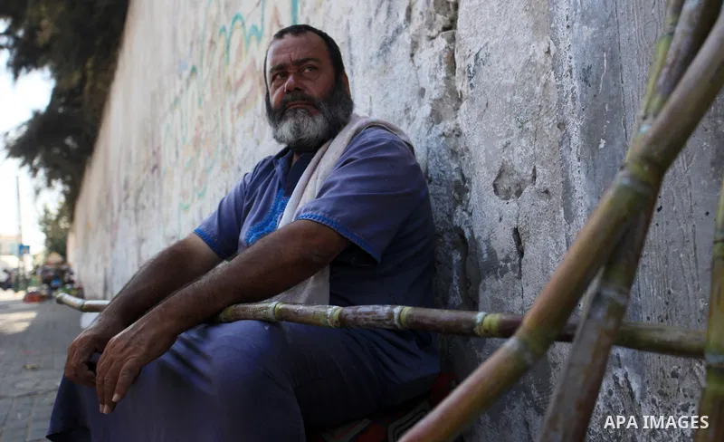 A Palestinian man sells sugar cane to students at a street, in Gaza city, on October 2, 2019. Photo by Mahmoud Ajjour