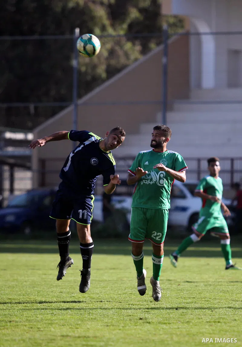 Palestinian football players of Etihad All-Shijaiyah (Green) and Al-Hilal (Dark blue) compete during match premier League in Alyarmuk stadium, in Gaza City, on October 7, 2019. Photo by Mahmoud Ajjour