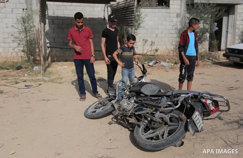 Palestinians gather around a motorcycle destroyed in an Israeli airstrike in Gaza city on November 13, 2019. Photo by Ashraf Amra