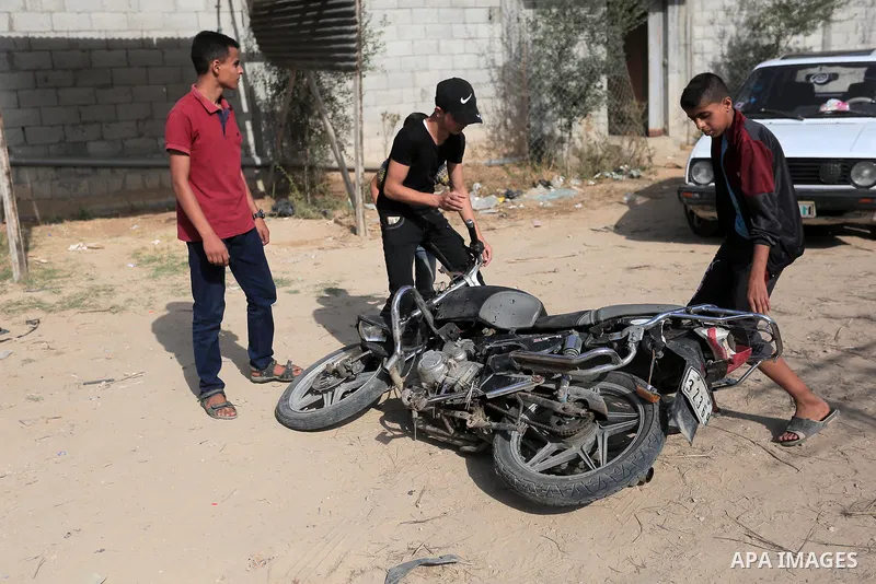 Palestinians gather around a motorcycle destroyed in an Israeli airstrike in Gaza city on November 13, 2019. Photo by Ashraf Amra