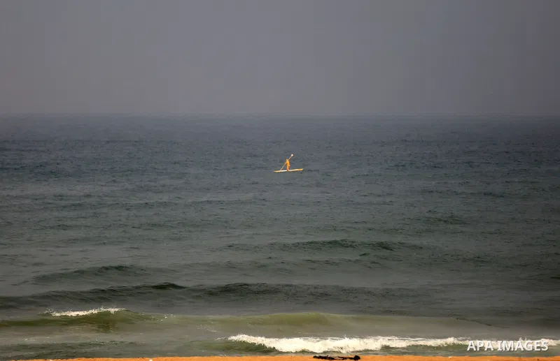 A Palestinian fisherman rides his boat during a rainy day at the coast of Gaza city. Photo by Yasser Qudih
